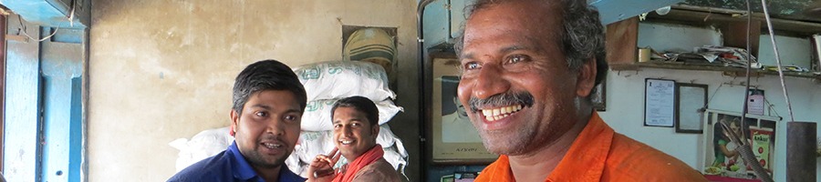 three Indian men smiling in a kitchen